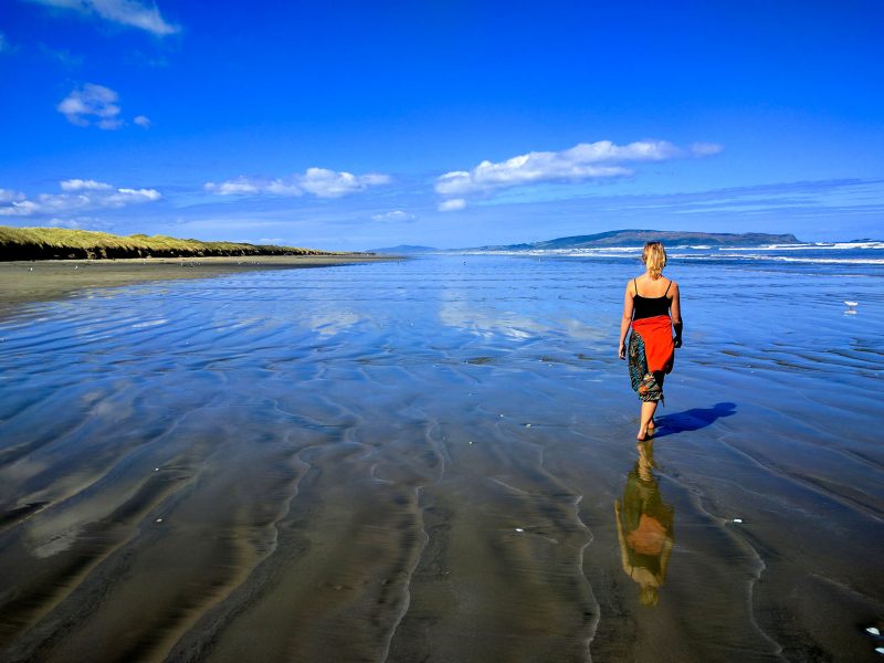 Woman walks along New Zealand beach