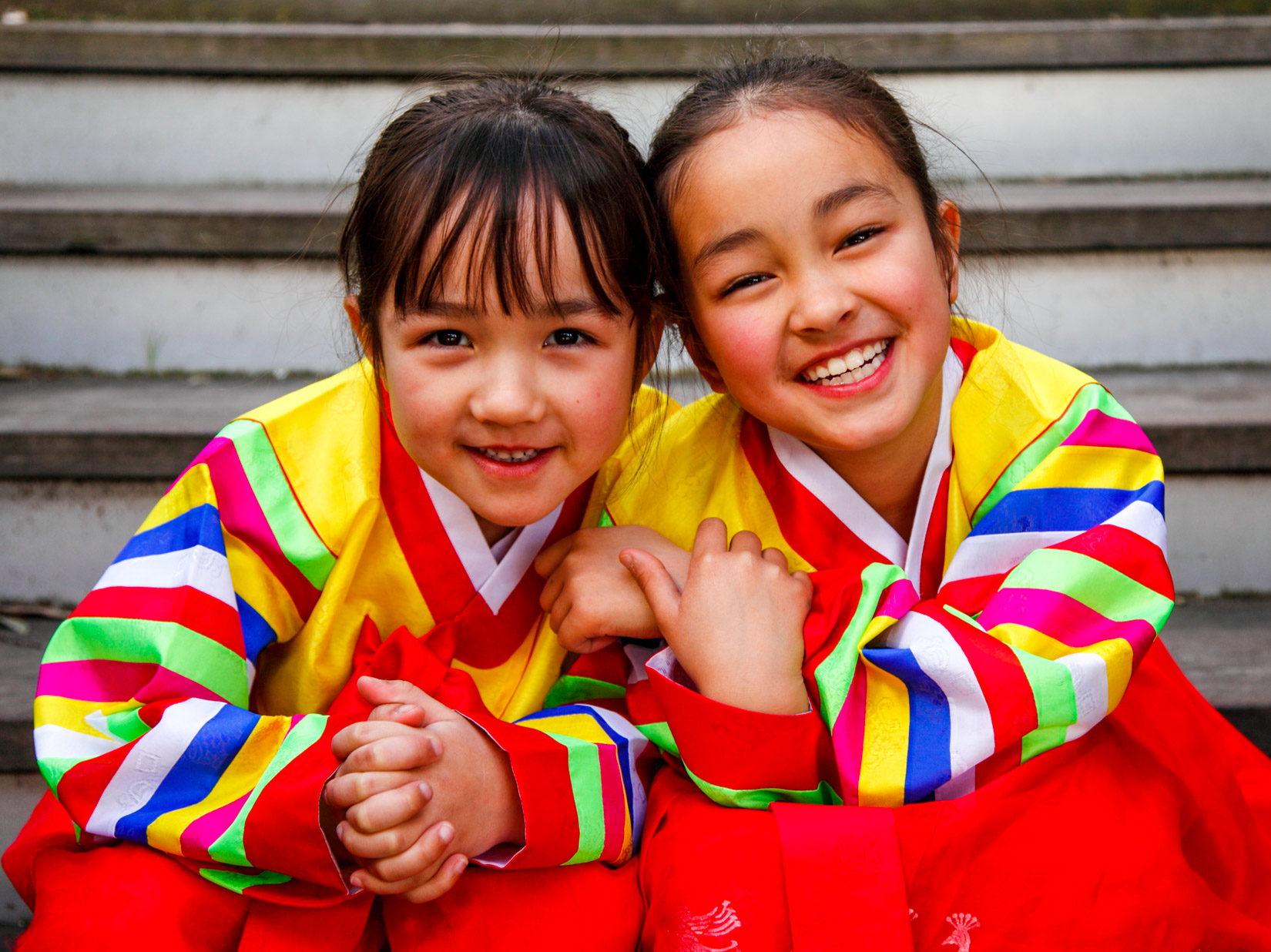 Two young girls in colorful hanboks smile brightly